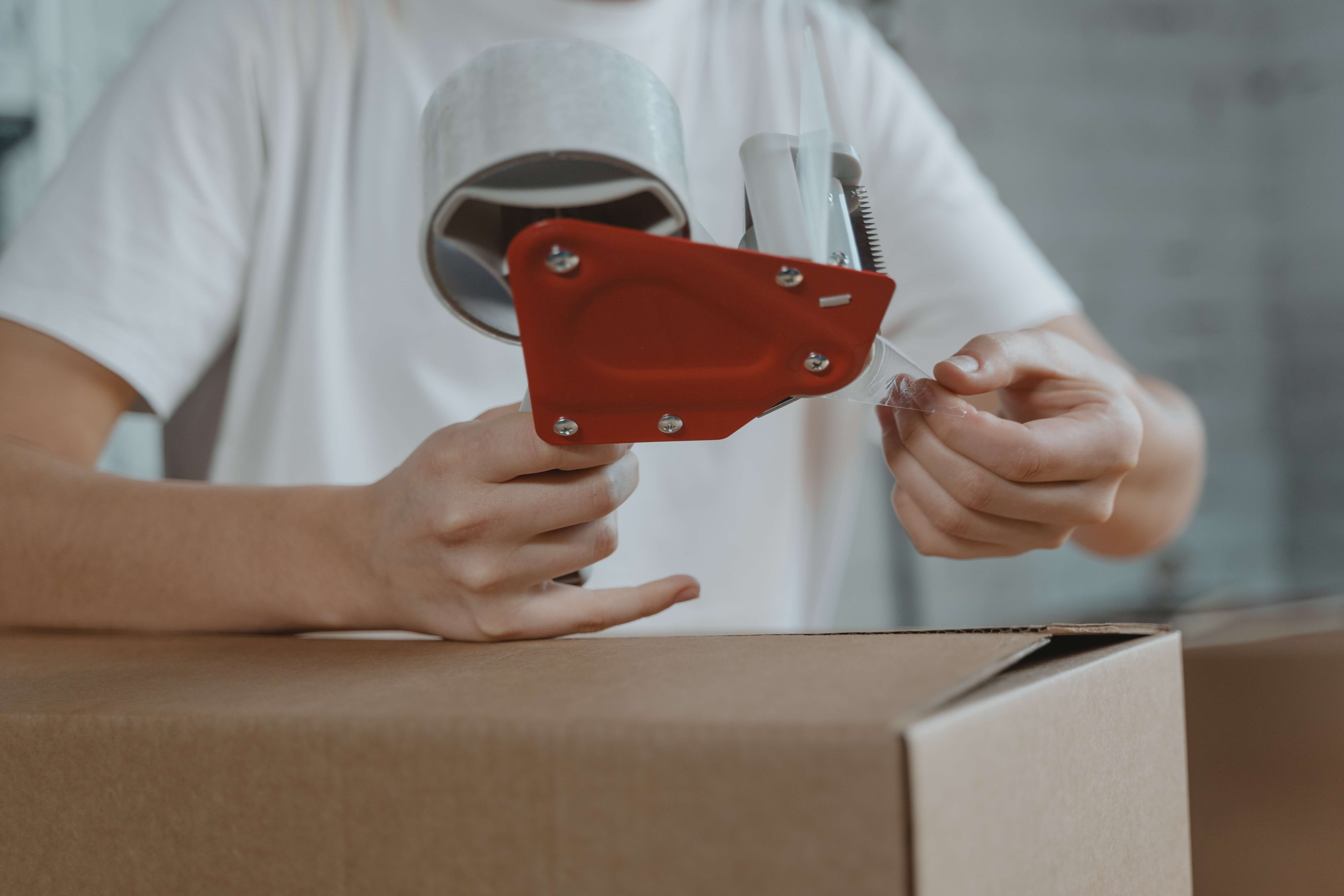  a person seals a box with wholesale channel letter sign parts with packing tape