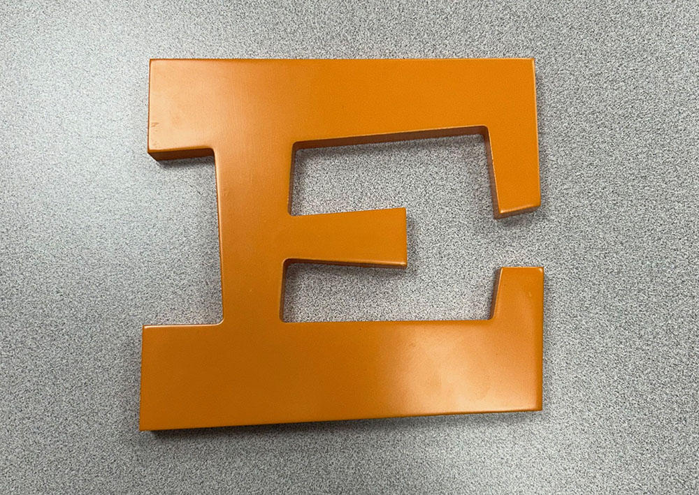 a orange letter on a grey surface
