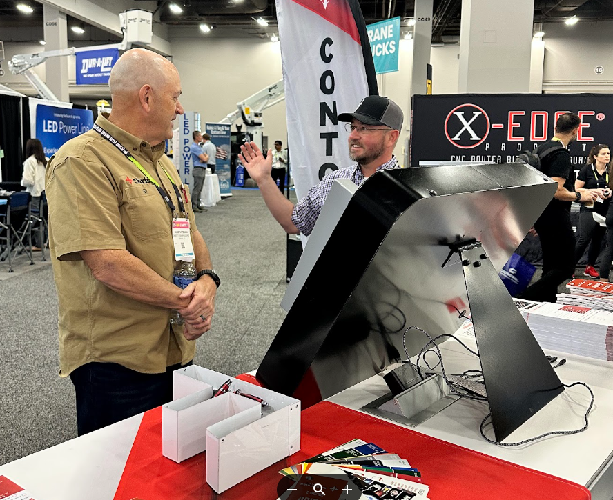 Customer conversation with DSW team member holding wireway sample at ISA 2025.